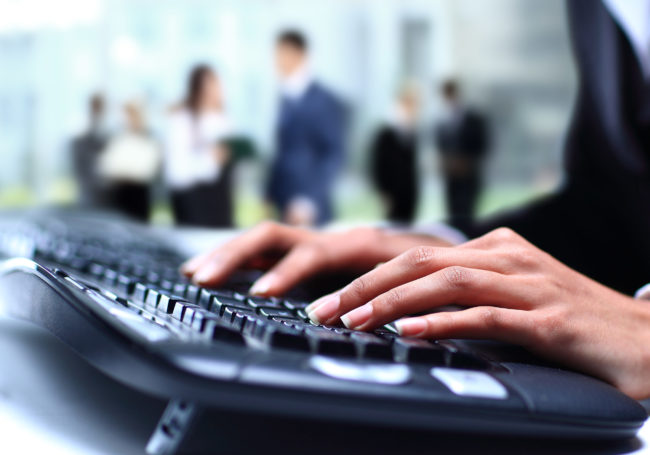 Human hands working on laptop on office background Bacteria are easily transferred on shared keyboards