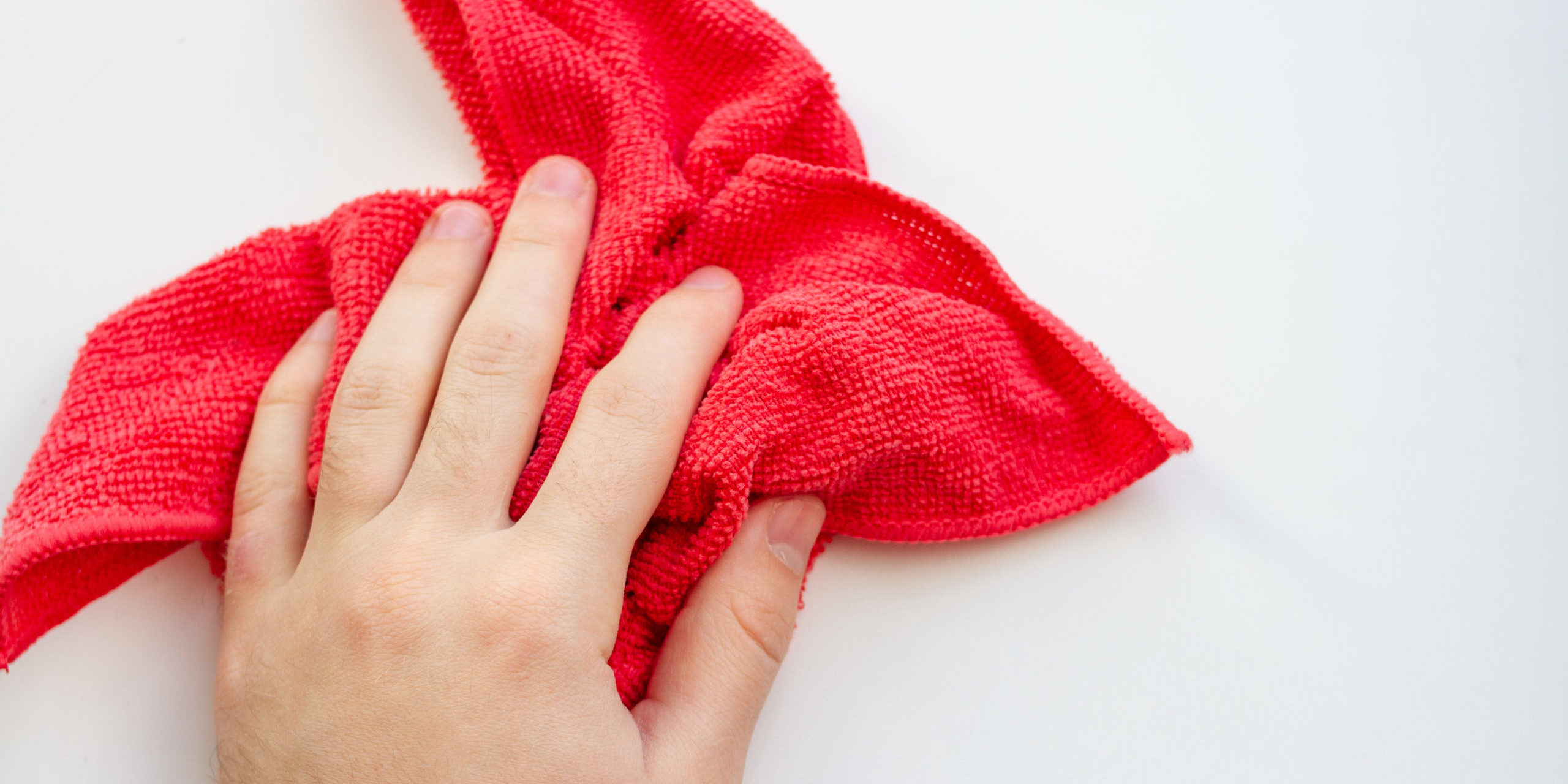 hand with red microfiber cloth on a white background. House cleaning Red microfibre cloth
