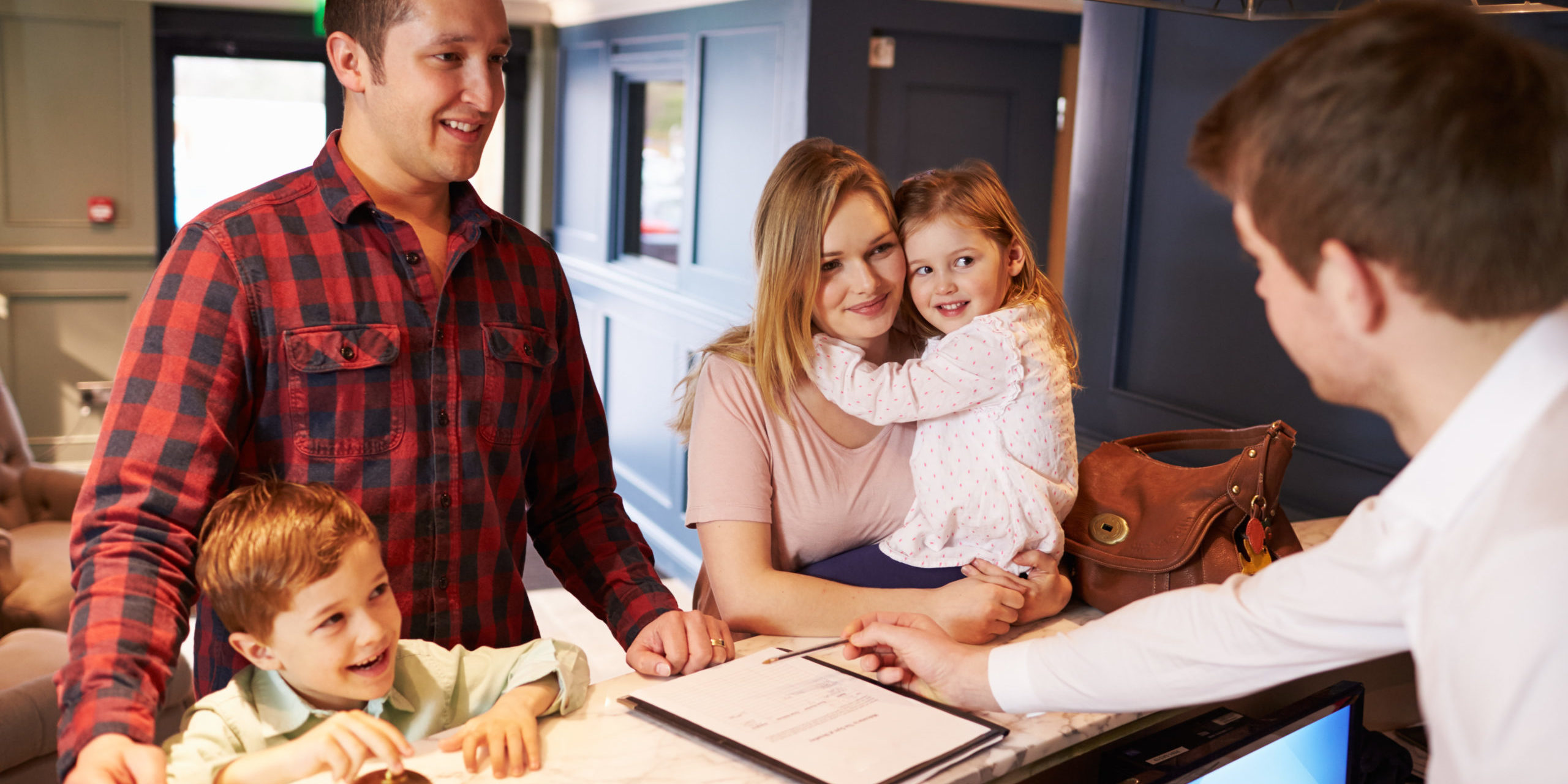 Family Checking In At Hotel Reception Desk